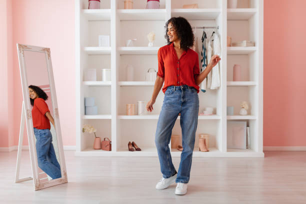 istock Content woman in red blouse and jeans by a mirror 2166927700