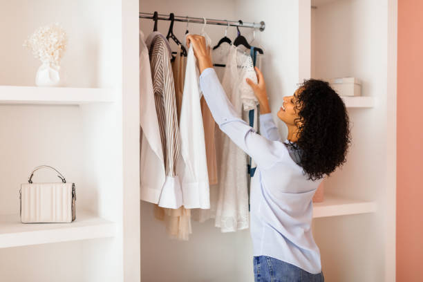 istock Curly-haired woman browsing clothes in a stylish closet 2166927708