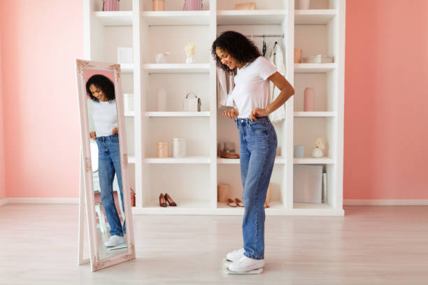 istock Latin woman in jeans smiling at her reflection 2166927730
