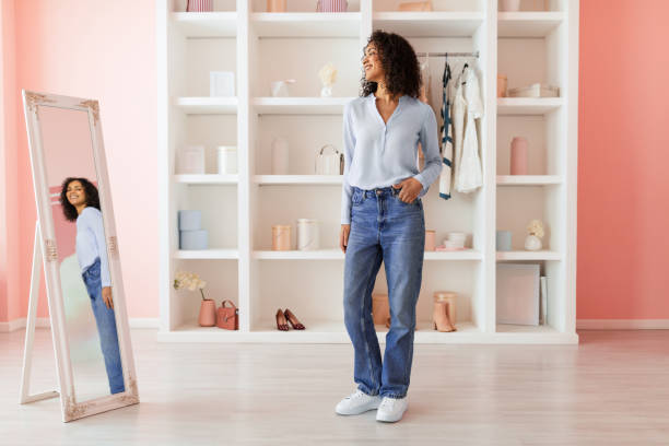 istock Content woman in jeans and blouse admires her reflection 2166927736