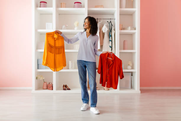 istock Woman comparing shirts while organizing her wardrobe 2166927746