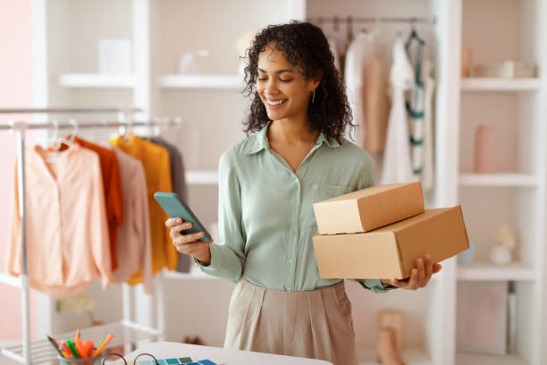 istock Cheerful entrepreneur with packages and phone in office 2166927756