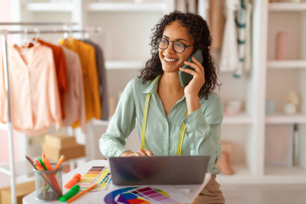 istock Happy designer with phone and laptop in a sunny studio 2166927758