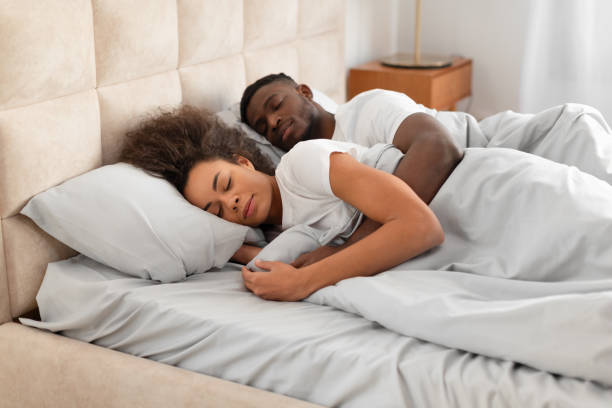 istock Young affectionate african american spouses sleeping in bed embracing indoor 2166928089