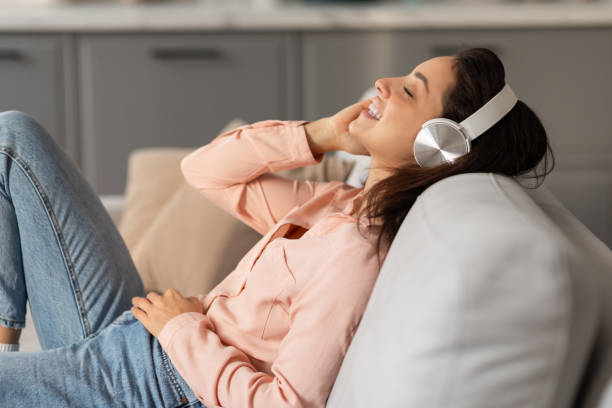 istock Joyful woman lying on couch with headphones, feeling relaxed 2166928792