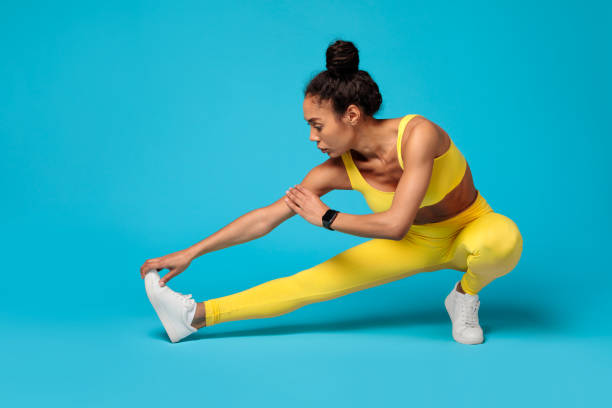 istock Focused athlete stretching in yellow outfit on blue background 2166928839