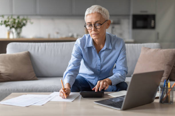 istock Mature lady entrepreneur working with laptop at home taking notes 2166928917