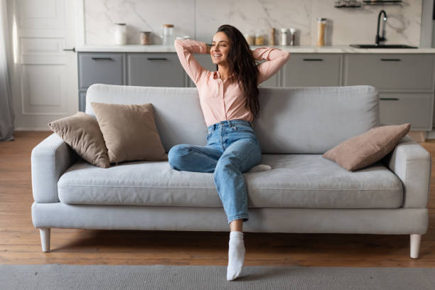 istock Joyful relaxed woman resting on couch with hands behind head 2166929149