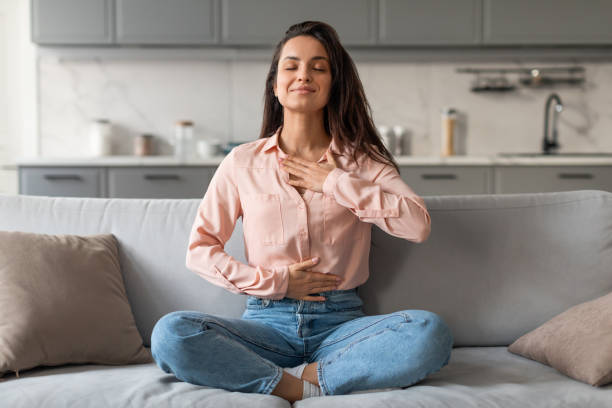 istock Relaxed young woman meditating on sofa at home 2166929155