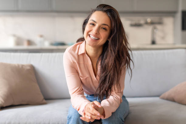 istock Cheerful woman sitting on grey couch, smiling 2166929196