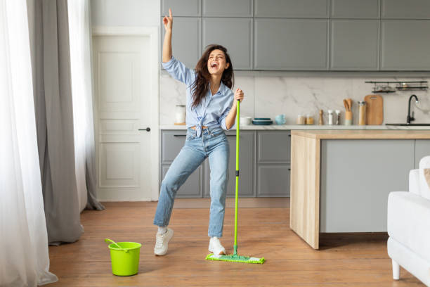 istock Joyful young woman dancing with mop in stylish kitchen 2166929199