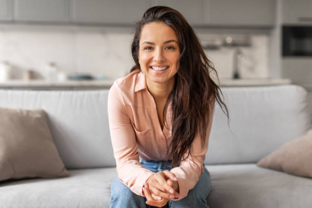 istock Confident woman smiling, sitting casually on grey couch 2166929202