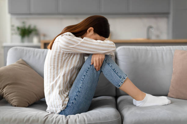 istock Upset young woman sitting on the sofa with her head down, side view 2166929606