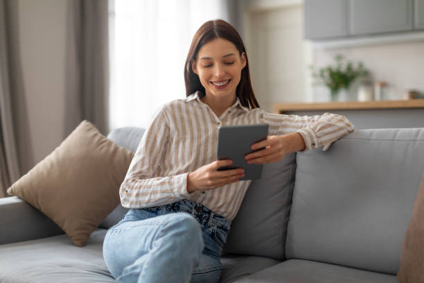 istock Smiling young woman relaxing with tablet on sofa 2166929646