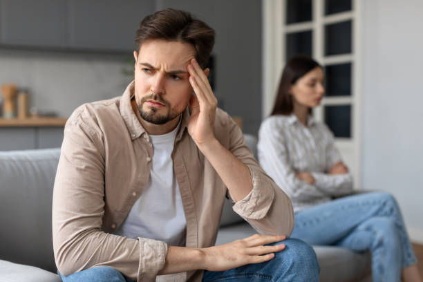 istock Concerned man with hand on head, distant woman behind 2166929679