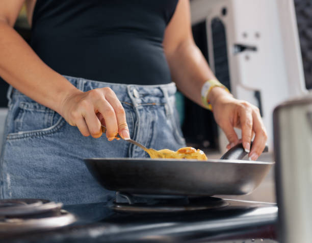 istock Young attractive woman cooking scramble eggs in the beach. 2166931280