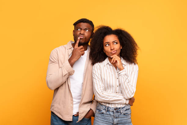 istock Thoughtful black couple with curious expressions on yellow 2166932050