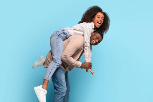istock Joyful black couple playing piggyback on a light blue background 2166932055