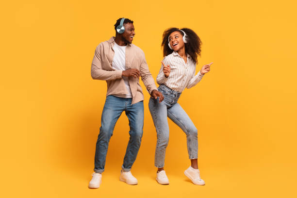 istock Happy black couple dancing with headphones on yellow backdrop 2166932072