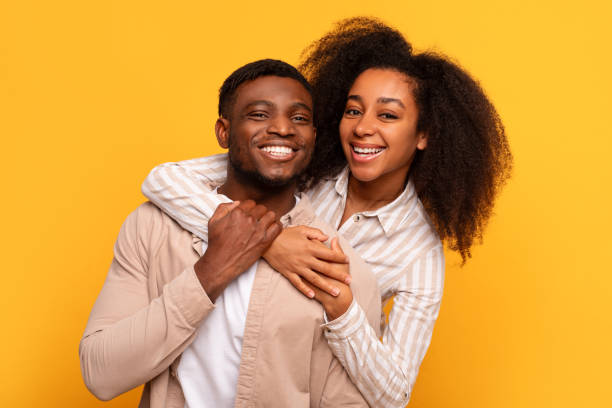 istock Cheerful black couple embracing on yellow background 2166932074