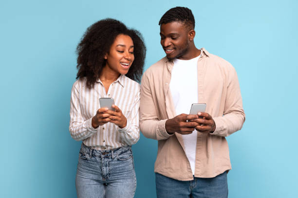 istock Smiling black couple with phones enjoying tech 2166932087