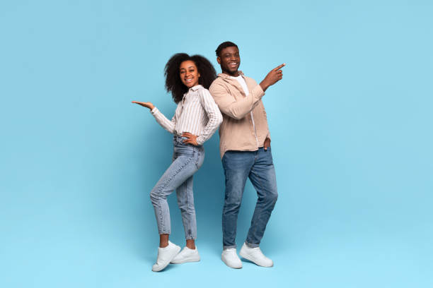 istock Happy black couple pointing sideways at free space on blue background 2166932088
