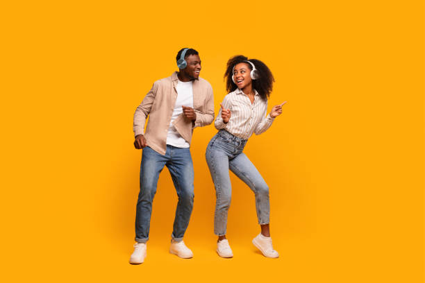 istock Dancing couple with headphones on yellow background 2166932171