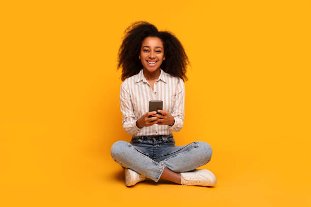 istock Smiling woman texting on smartphone on yellow background 2166932172