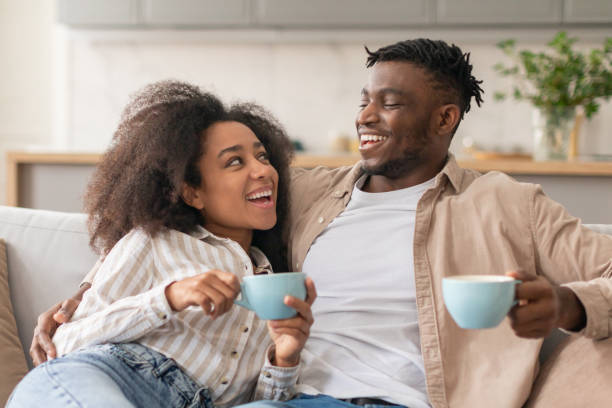 istock Cheerful Black Couple Drinking Coffee Relaxing On Sofa At Home 2166932463