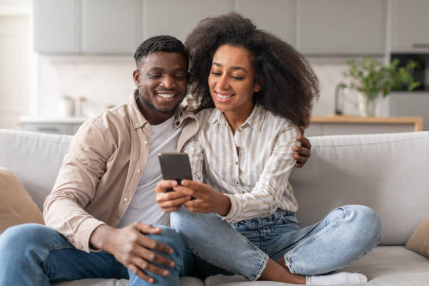 istock African couple on sofa having fun with smartphone at home 2166932557
