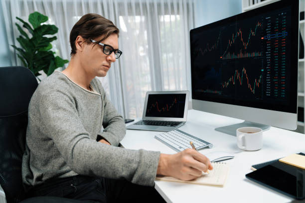 istock Trader in casual day taking note in stock exchange market graph. Pecuniary. 2166933231