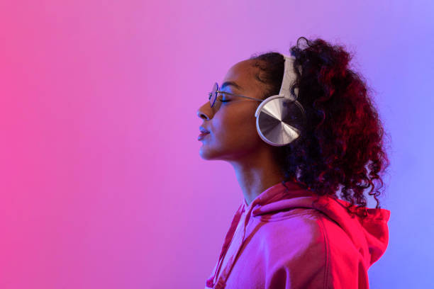 istock Serene black lady with headphones against neon backdrop, side view, free space 2166933430