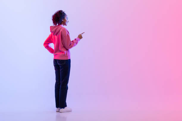 istock Rear view of woman pressing invisible button on gradient backdrop 2166933478