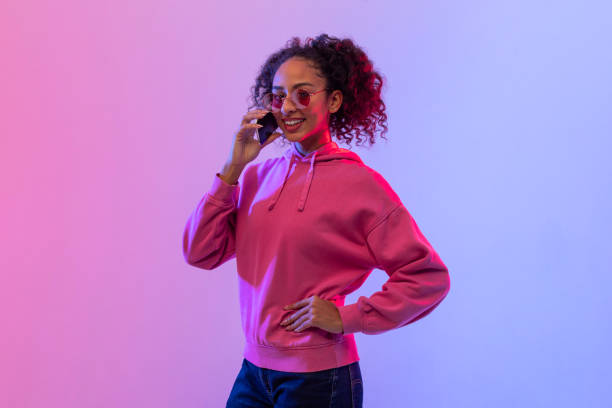 istock Stylish black woman talking on phone with neon backdrop 2166933482