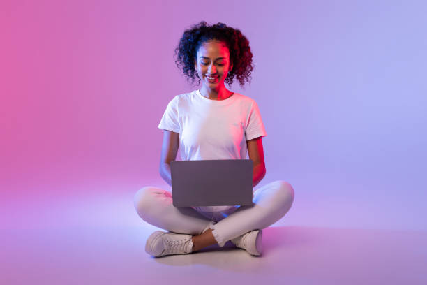 istock Smiling woman sitting with laptop on floor 2166933559