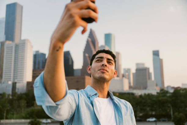 istock Handsome latin man takes a selfie with urban skyline 2166933672