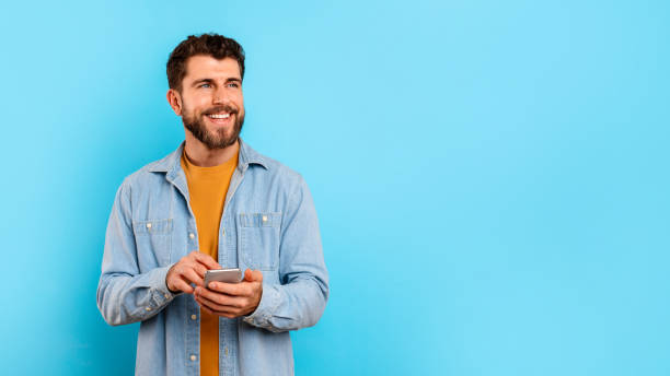 istock man texting on mobile phone near free space, blue background 2166933839