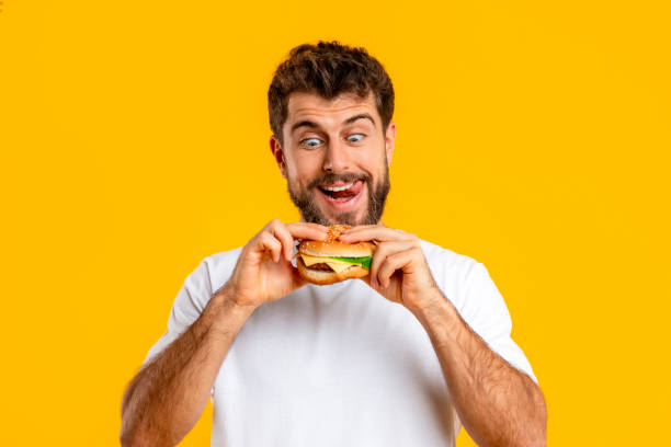 istock Funny hungry bearded man looks at burger with temptation, studio 2166933843