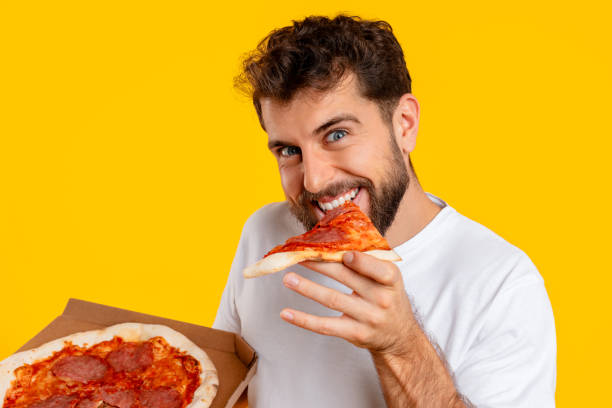 istock Cheerful guy bites into a slice of pizza in studio 2166933851