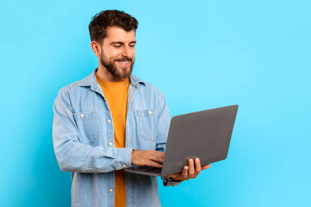 istock Happy young man typing on his laptop websurfing in studio 2166933870