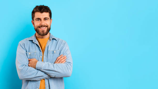 istock Happy millennial guy confidently stands with arms crossed in studio 2166933876