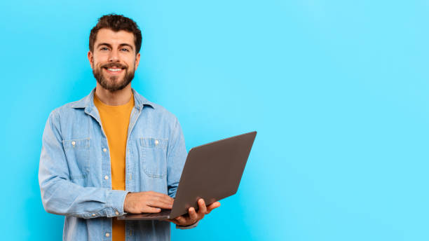 istock guy working on laptop posing with gadget on blue background 2166933878