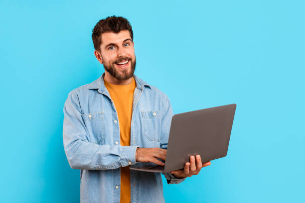 istock Cheerful millennial man casually dressed browsing internet on laptop, studio 2166933900