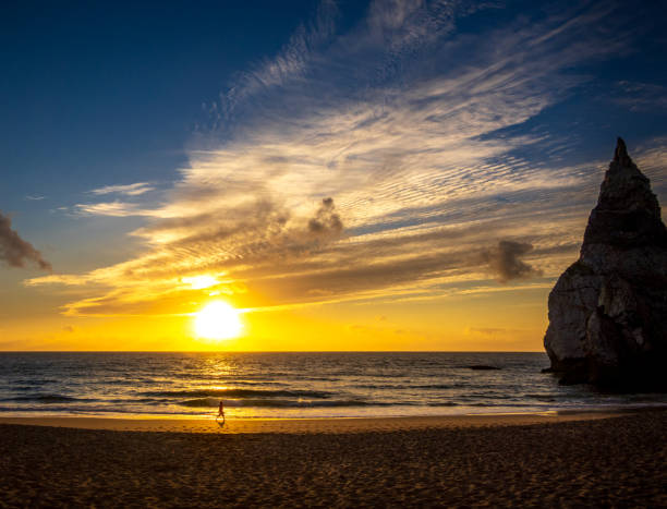istock Sunset at the beach with clouds and someone walking 2166934025