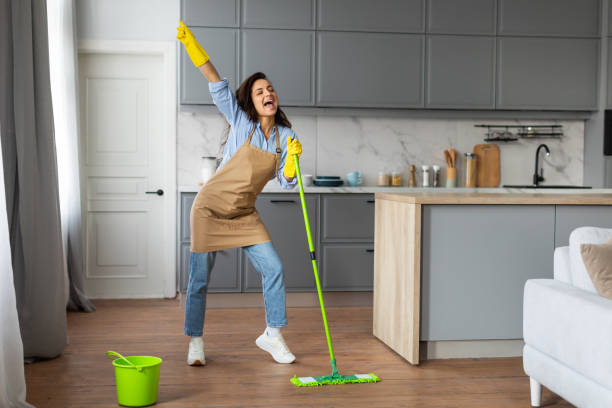 istock Joyful woman singing with mop like microphone in kitchen 2166934814