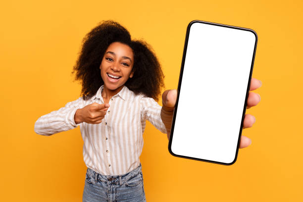 istock Happy black woman presenting smartphone screen on yellow background 2166934856