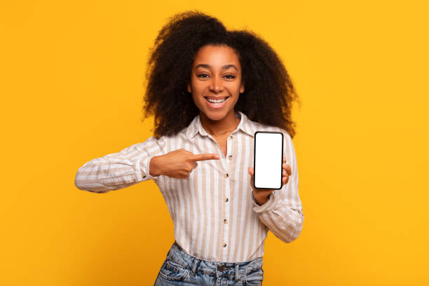 istock Happy black lady showing smartphone blank screen on yellow background 2166934869