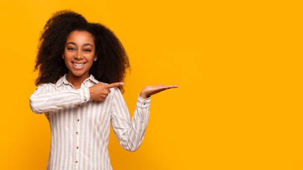 istock Young woman presenting with hand gesture on yellow background 2166934904