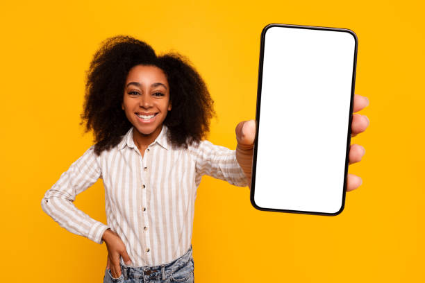 istock Smiling woman displaying smartphone screen on yellow background 2166934914