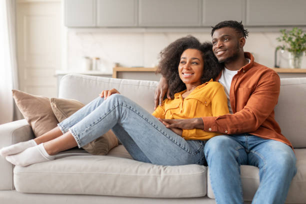 istock Smiling African American Spouses Embracing While Relaxing On Couch Indoors 2166934962